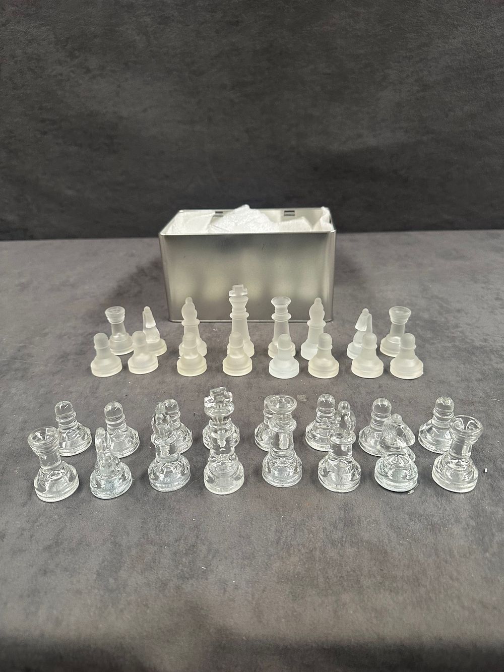Lot 253: A Set of Thirty-Two Miniature Glass Chess Pieces with a Metal Storage Tin
