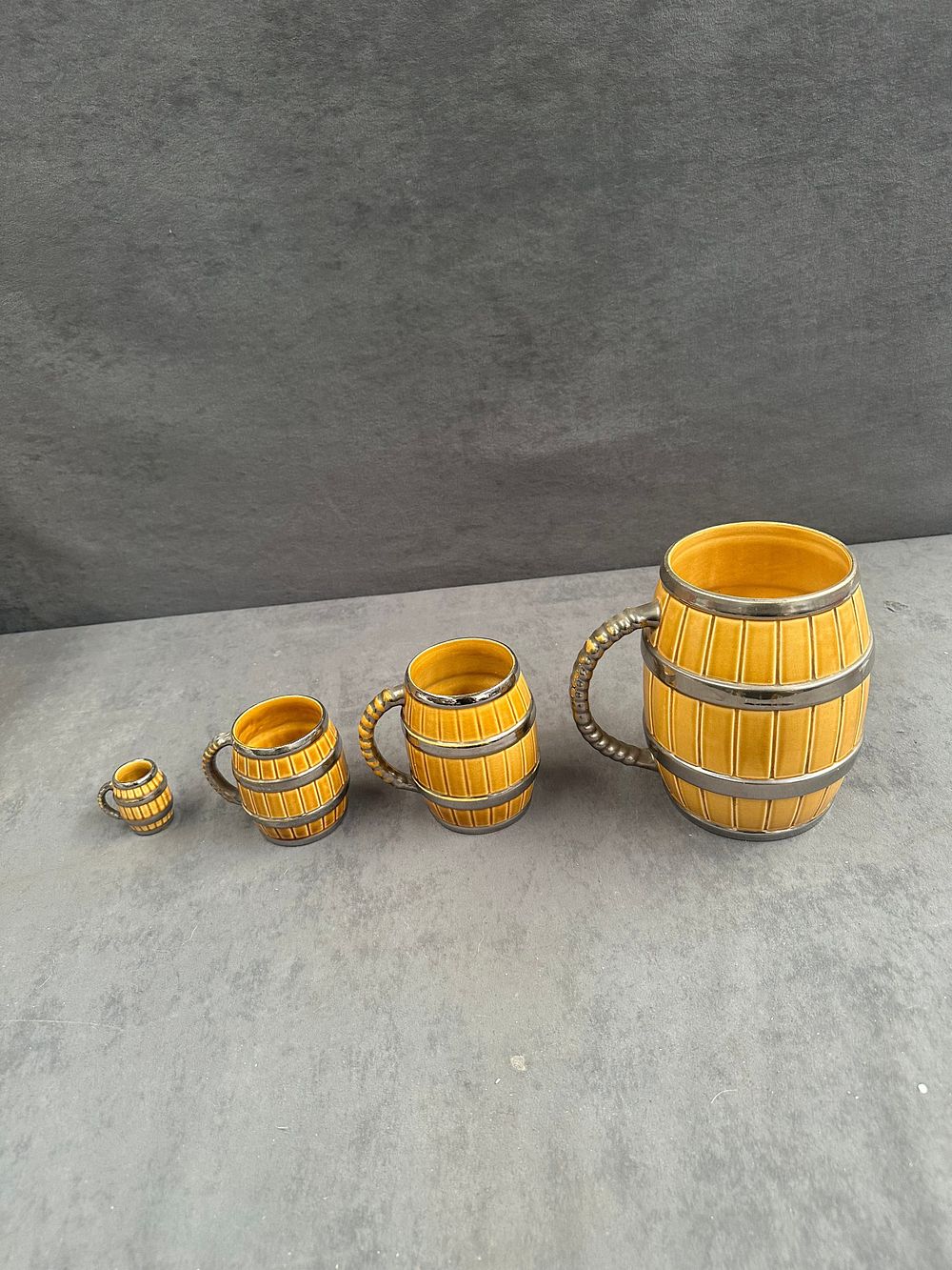 Lot 764: A Set of Four Graduated Mustard Yellow and Silver Lustre Ceramic Barrel Mugs
