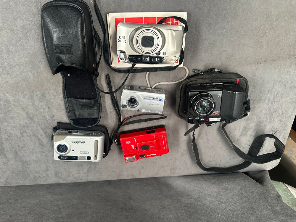Lot 457: An Assortment of Vintage Compact Film and Digital Cameras including Pentax, Olympus, and Ricoh