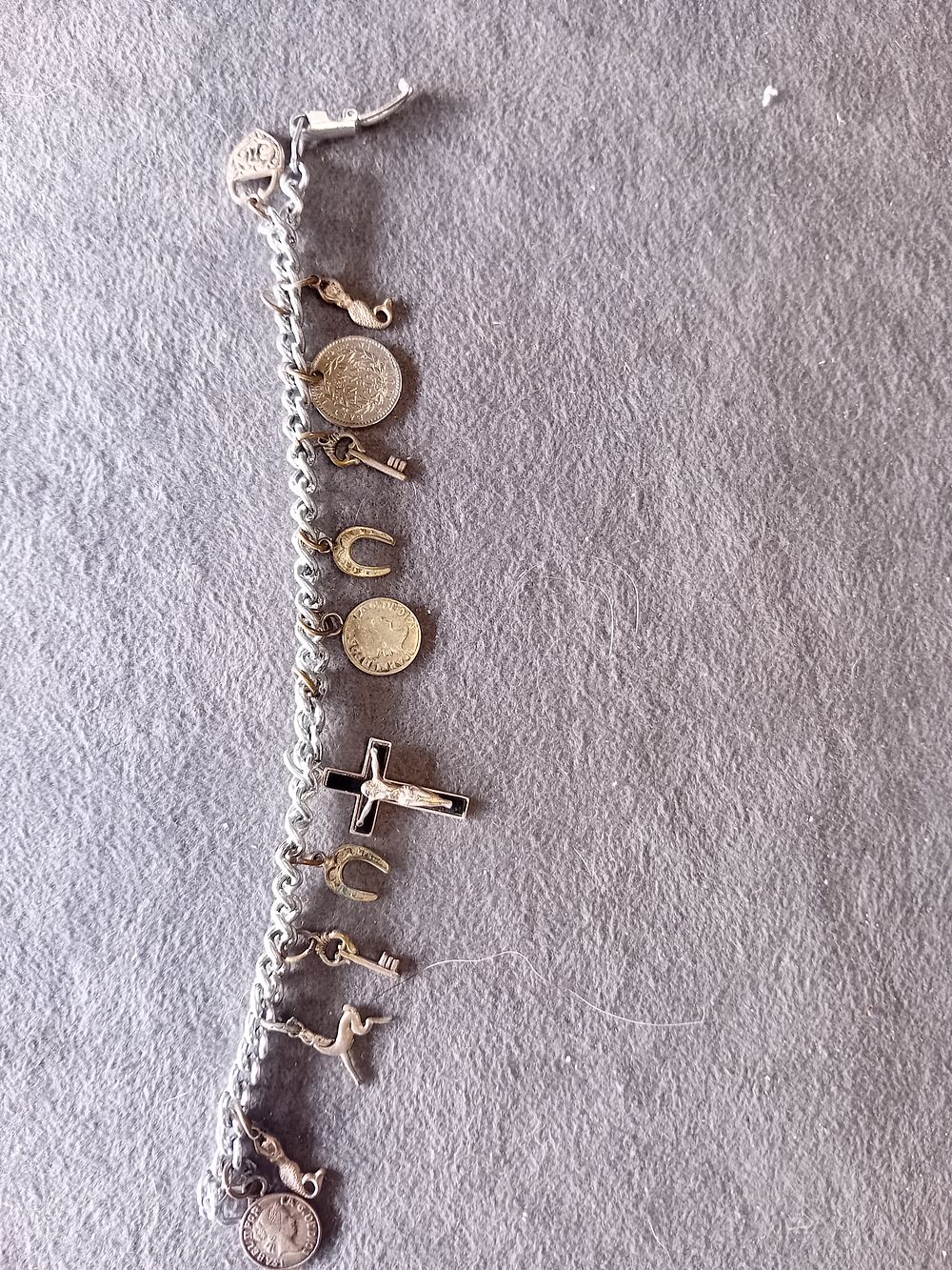 Lot 557: SILVER TONE CHARM BRACELET WITH COINS AND RELIGIOUS CHARMS