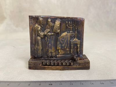 תבליט יודאיקה. תבליט מתכתי עם סצנה דתית ומנורה בסגנון וינטג׳