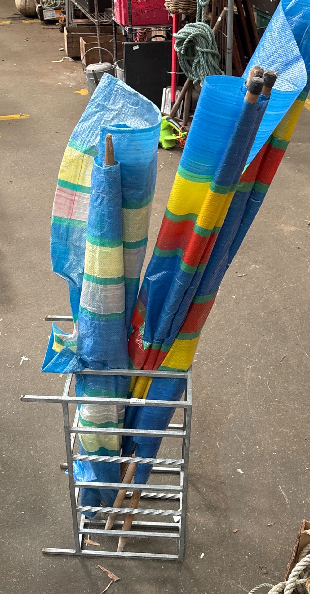 Lot 112: A Galvanised Metal Storage Stand and Several Multi-Coloured Beach Windbreaks
