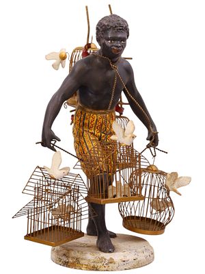 A CONTINENTAL POLYCHROME-DECORATED FIGURE OF A BIRD SELLER (BLACKAMOOR SUBJECT), AUSTRIAN OR 