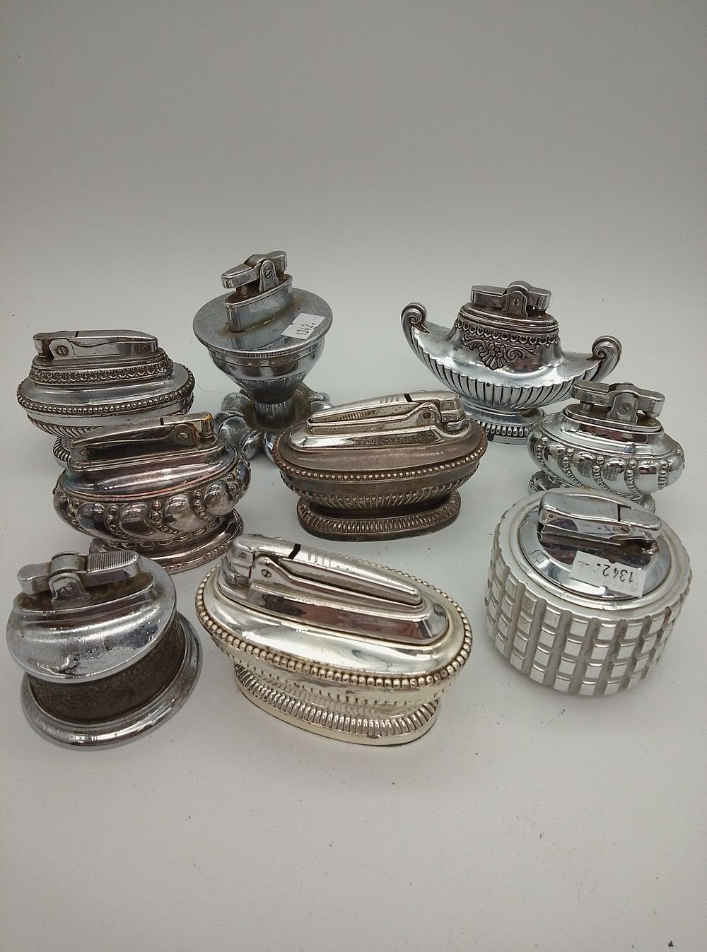 Lot 214: 9 white metal 1970s vintage lighters featuring Calibri...