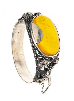 Amber clasp bangle in silver with floral decorative elements, featuring a large, oval amber 