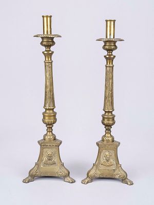 Pair of altar candlesticks, c. 1900, brass. Trefoil base on lion’s paws, each with three saint 