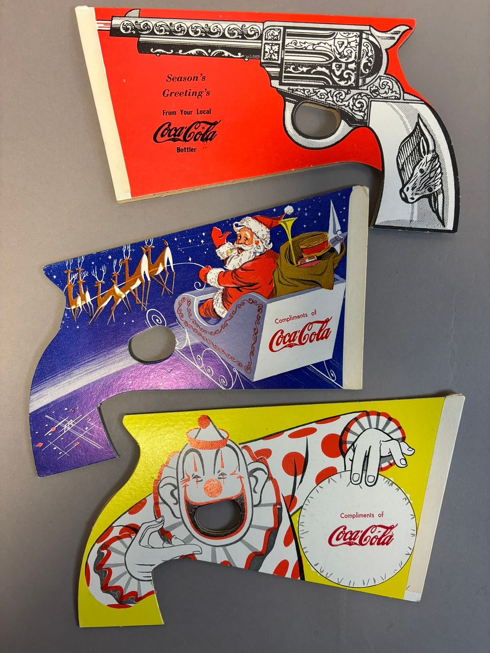 Lot 348: Lot 3 Original Coca Cola Clown Santa & Gun Related Toy Paper Advertising Guns