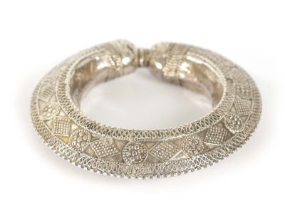 A 19TH CENTURY SILVER AFRICAN TRIBAL BANGLE with embossed decoration. (7cm internal diameter)