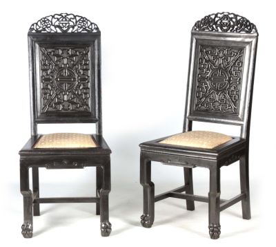A PAIR OF CHINESE HARDWOOD CHAIRS with carved pierced top rails above carved panelled backs and 