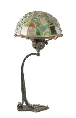 AN ART NOUVEAU IRONWORK ELECTRIFIED LAMP BASE with pivoting light fitting on a scrolling leaf 