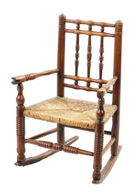 A 19TH CENTURY FRUITWOOD CHILDS ROCKING CHAIR with turned spindle back and rush seat; raised on 