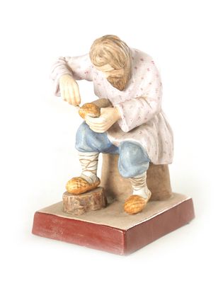 A RUSSIAN IMPERIAL SEATED FIGURE OF A COBBLER decorated in pastel shaded on a brown-edged base. 
