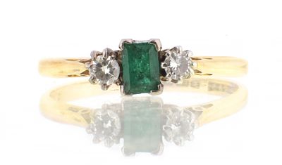 AN 18CT GOLD EMERALD AND DIAMOND RING with baguette cut emerald flanked by two brilliant cut 