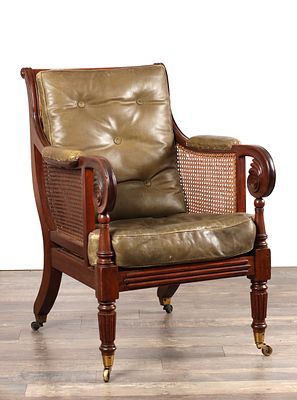 A GOOD REGENCY MAHOGANY BERGERE LIBRARY CHAIR the moulded frame with scroll arms and roundel 