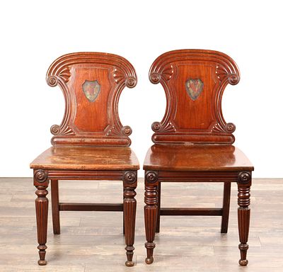 A PAIR OF REGENCY MAHOGANY HALL CHAIRS IN THE MANNER OF GILLOWS with painted shield-shaped 