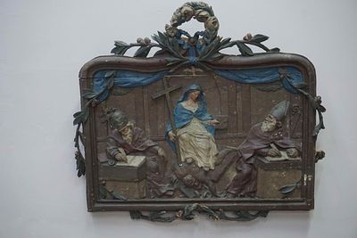 Polychrome, framed bas-relief in wood. The central figure depicts Mary holding a cross and 