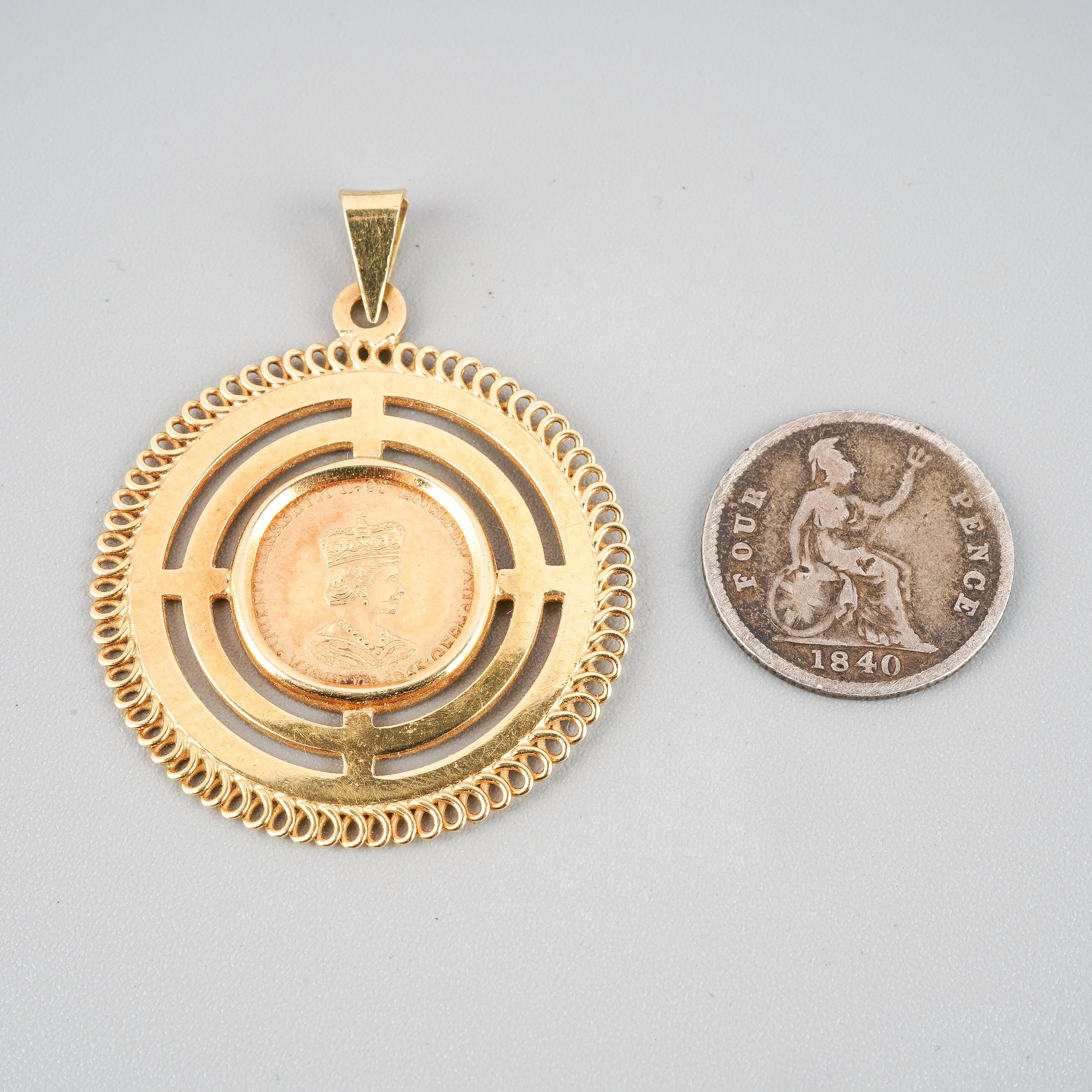 A yellow metal mounted (marked 585) 1965 gold coin