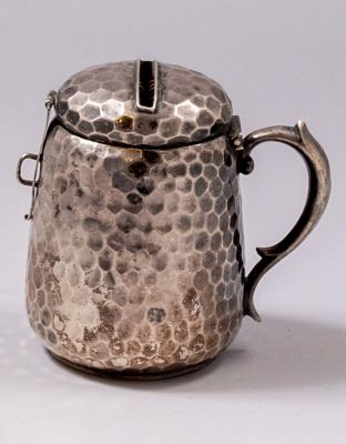 קופת צדקה גרמנית מכסף 800. מעוטרת בעבודת ריקוע. גובה: 8 ס"מ. משקל: 96 גרם. חתומה.