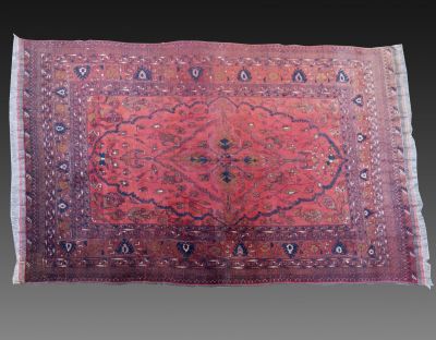 שטיח אפגני חל-ממדי מעוטר במוטיבים צמחיים וגיאומטריים. מידות (ללא גדילים): 298X190 ס"מ. פגמים קלים.