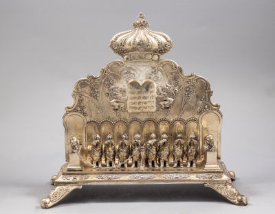 חנוכיית כסף גרמנית, סגנון ניאו קלאסי, סוף המאה ה-19. גב החנוכייה מעוטר בלוחות הברית ואריות 