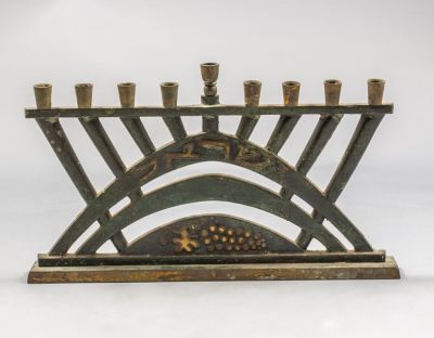 חנוכיית פליז, פל בל. חנוכיית פליז ישראלית תוצרת פל-בל שנות ה-50. מעוטרת ענבים. רוחב: 24.5 ס"מ. חתומה.