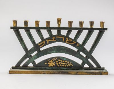 חנוכיית פליז, פל-בל. חנוכיית פליז ישראלית תוצרת פל-בל שנות ה-50. מעוטרת ענבים. רוחב: 24.5 ס"מ. חתומה.