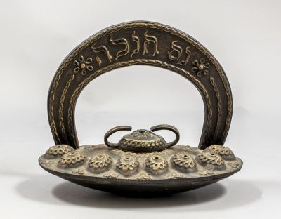 חנוכיית שמן, נתן שלגמן. חנוכיית שמן מפליז תוצרת שלגמן. מעוטרת בדוגמאות פרחוניות ובכיתוב: "נס 