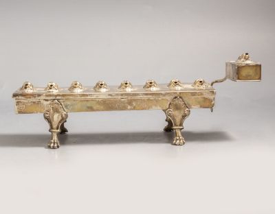 חנוכיית שמן גרמנית מכסף. חנוכיית שמן מכסף, ככל הנראה גרמניה, המחצית הראשונה של המאה ה-19. מעוטרת 