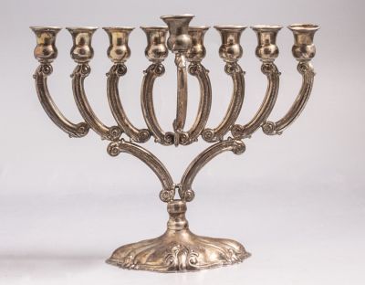 חנוכיית כסף 925, מעוטרת בעבודת בלט של מוטיביים צמחים. גובה: 21 ס"מ. משקל: 274 גרם. חתומה.