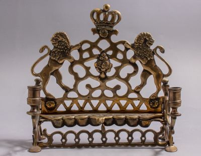 חנוכיית פליז פולנית מעוטרת בעבודה פתוחה במראה אריות, כתר ומוטיבים גיאומטריים. גובה: 24.5 ס"מ.