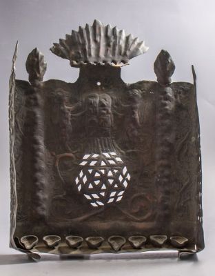 חנוכייה עממית מנחושת. חנוכיית נחושת, עבודה עממית. מעוטרת בעבודת חסר ובלט של אריות ומוטיבים 