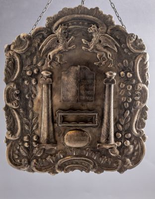 טס לספר תורה מצופה כסף. מעוטר בעבודת בלט במראה גריפונים, לוחות הברית, עמודים, כתר ומוטיבים 