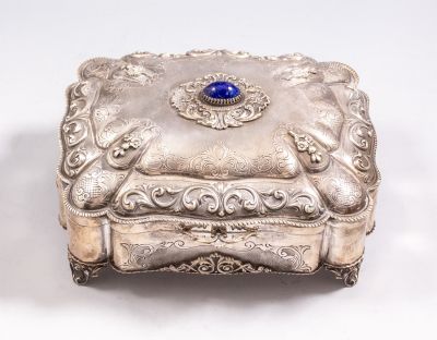 קופסת כסף איטלקית מעוטרת בעבודת בלט וחריטה עם מוטיבים צמחיים ומשובצת לפיס לזולי. ניצבת על 4 