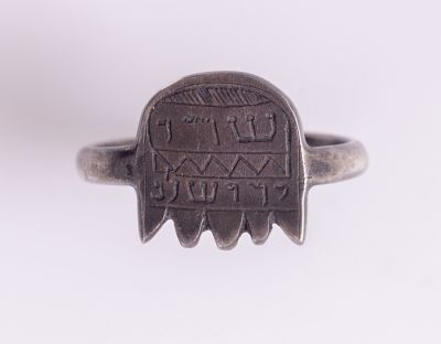טבעת קמע מכסף עם הכיתוב " שדי ירושלם". מידות הקמע: 13X13 מ"מ.