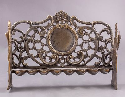 חנוכיית פליז בוהמית, פראג, המאה ה-18. גב החנוכייה מעוטר בעבודה פתוחה ובתבליטים. במרכזו, מדליון 