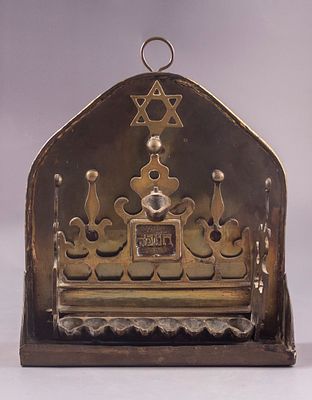 חנוכייה הולנדית, ראשית המאה ה-19. נתונה בתוך בית קיבול מפח-פליז עם ידית לתלייה, דפנות צד ומיכל 