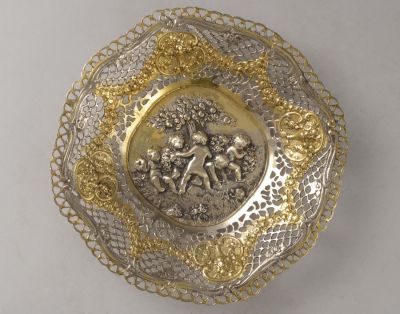 קערת כסף 800 בסגנון ניאו-קלאסי. מעוטרת בתבליט עם דמויות פוטי, בהזהבות ובעבודה פתוחה. קוטר: 18 