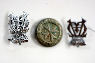 שני סמלים בריטיים של נהגי אמבולנס במלחמת העולם השנייה, 1939–1945, וכפתור של בגדו.