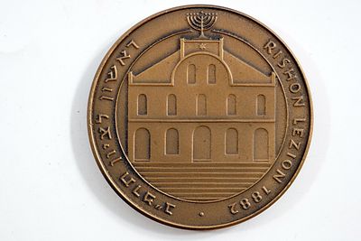 מדליה של האמן יעקב אגם – מדליית המאה לרגל 100 שנה ליסוד ראשון לציון, ארד, קוטר 59 מ"מ; בחזית 