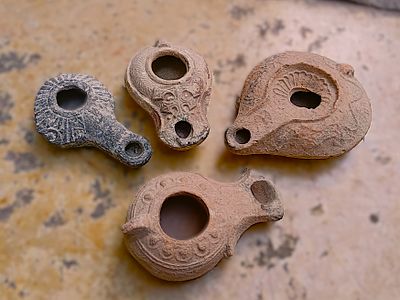 ארבעה נרות חרס. Lot of four lamps: Hellenistic with black slip and delphinoform handle, Jerash 
