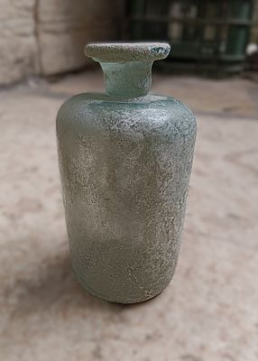 כלי זכוכית עתיקה. Bottle, cylindrical with short neck and flat rim folded under; pushed in base; 
