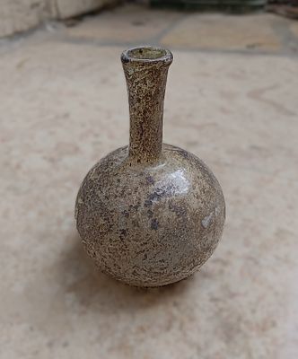 כלי זכוכית עתיקה. Bottle with long neck; slightly everted rim folded inwards; round body; pushed 
