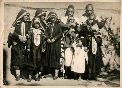 תצלום אחד של משפחה יהודית תימנית. שני הגברים לובשים טלית ומחזיקים תינוקות בזרועותיהם. גודל: 