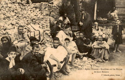 גלויה עם יהודי מרוקו בפאס יושבים מול ביתם ההרוס לאחר המהומות הערביות.