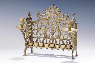 A LARGE BRASS HANUKKAH LAMP. Poland, c. 1800 On four feet with pierced backplate decorated with 