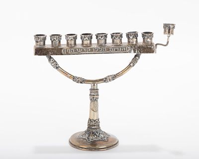 A MINIATURE STERLING SILVER MENORAH BY THE BEZALEL SCHOOL. Jerusalem, c. 1950. On a round base 