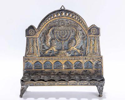 A SILVER PLATED HANUKKAH LAMP BY THE BEZALEL SCHOOL. Jerusalem, c. 1920. On four feet with 
