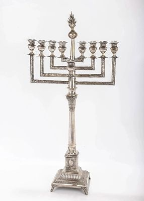 A LARGE SILVER MENORAH. Warsaw, c.1900. On an ornately decorated base in candlestick form. With 