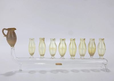 A GLASS MENORAH BY ZCUCAN. Israel, 20th century. On two supports with nine oil holders. 12.2 