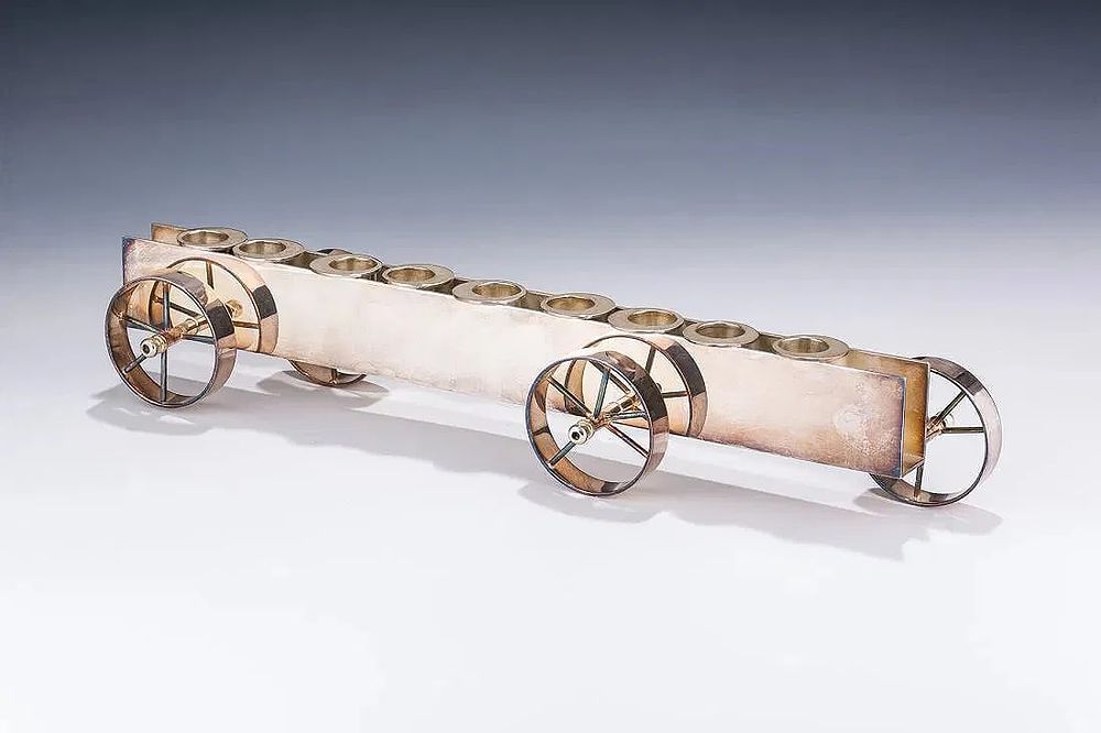 A STERLING SILVER CHANUKAH MENORAH BY PAMPOLINI. Italy. Italy. In the shape of a wheeled cart. 